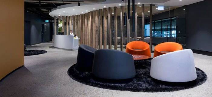 Modern office lobby with circular seating area featuring black and orange chairs, highlighting neurological adulthood theme.