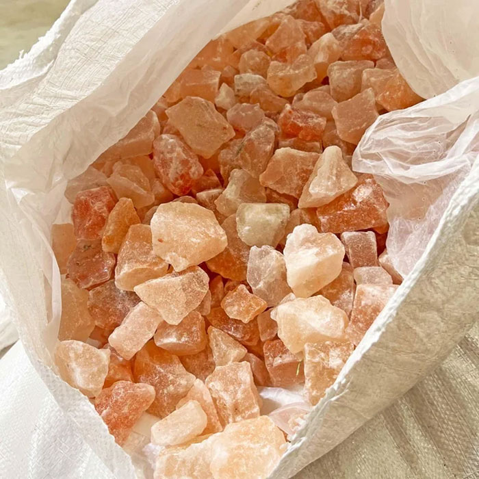 Close-up of assorted Himalayan salt crystals in a white bag, highlighting natural mineral textures and colors.