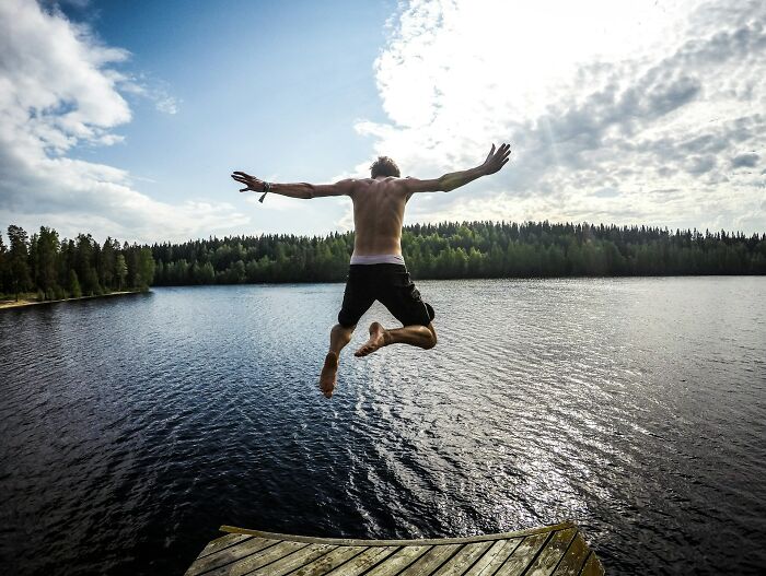 Person jumping into a lake surrounded by forest, illustrating vanished truths from people's home countries shared online.