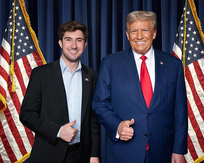 Turning Point USA college president standing with former president, both giving thumbs up in front of American flags.