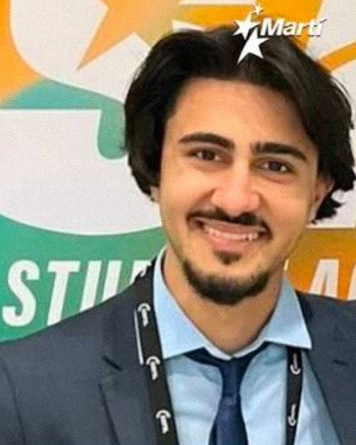 Turning Point USA college president smiling in a suit with a student organization logo background.