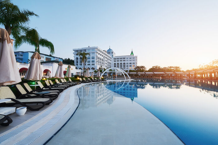 Empty poolside with lounge chairs and umbrellas at sunrise, reflecting a hotel in a calm, serene setting for customers’ complaints.