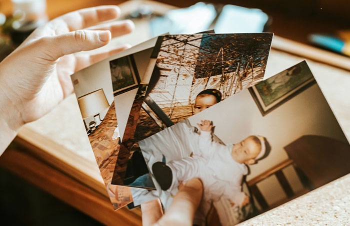 Hands holding a collection of old printed photos, illustrating rare and one-in-a-million stories people lived through.