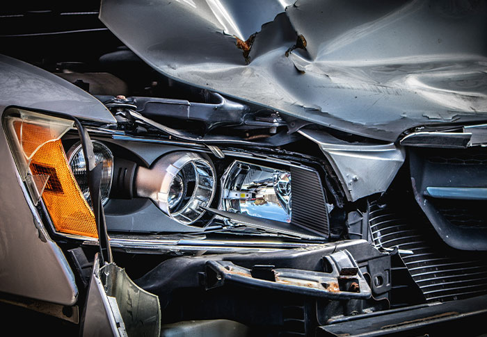 Close-up of a crashed car's damaged headlight and front hood illustrating rare one-in-a-million stories that are hard to believe.