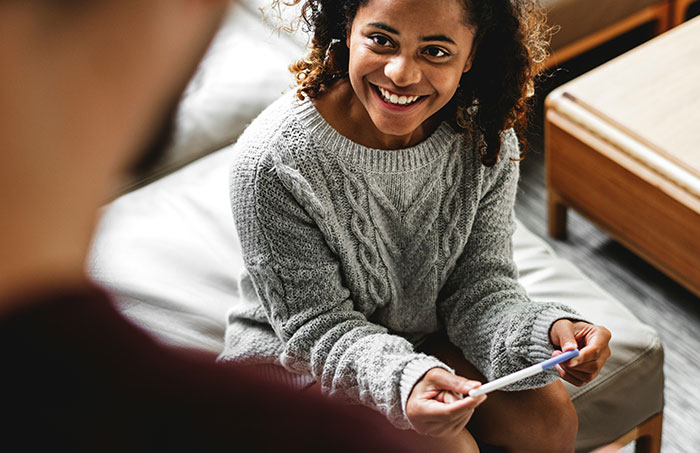 Young woman smiling and sharing a one-in-a-million story she actually lived through with another person.