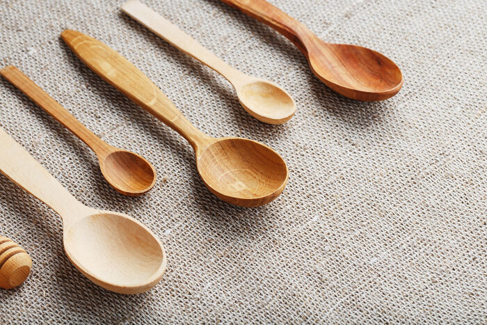 Various wooden spoons arranged on burlap fabric, symbolizing unconventional family traditions collection.