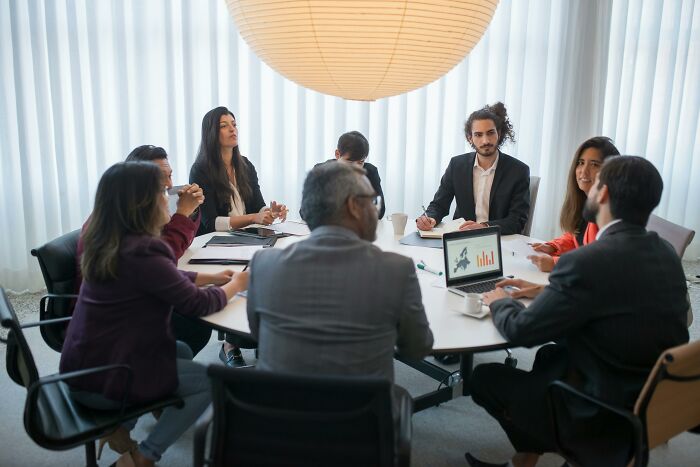 Group of diverse professionals in a meeting room engaging in a discussion about challenging beliefs and controversial opinions.