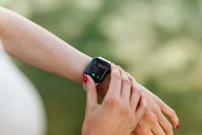 Person with red nail polish interacting with smartwatch, symbolizing challenge your beliefs and controversial opinions.