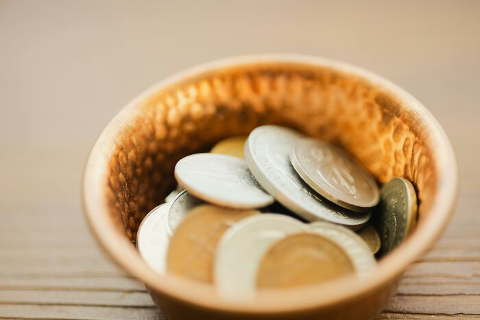 Close-up of coins in a textured bowl representing challenge your beliefs and controversial opinions concepts.