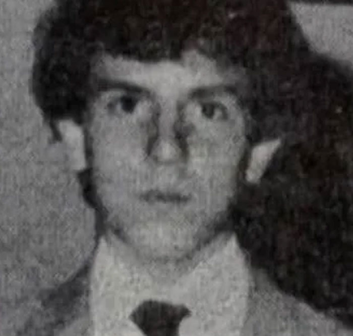 Black and white portrait of a young man in a suit, representing unsettling mysteries that continue to fascinate and disturb.