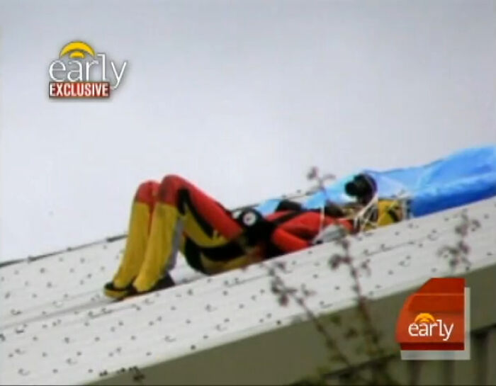 Rescue worker in red and yellow gear lying on a rooftop during a dramatic incident, showing disturbing real life nightmare scene.