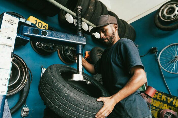 Man working with a tire machine in a shop, illustrating moments when people destroyed their own lives in an instant.