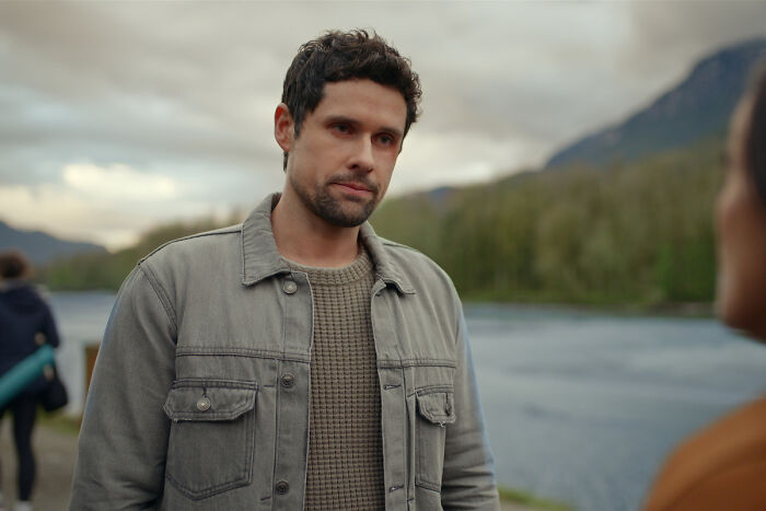 Man standing outdoors near a river, reflecting Virgin River star Brady in a tense Season 7 cliffhanger moment.