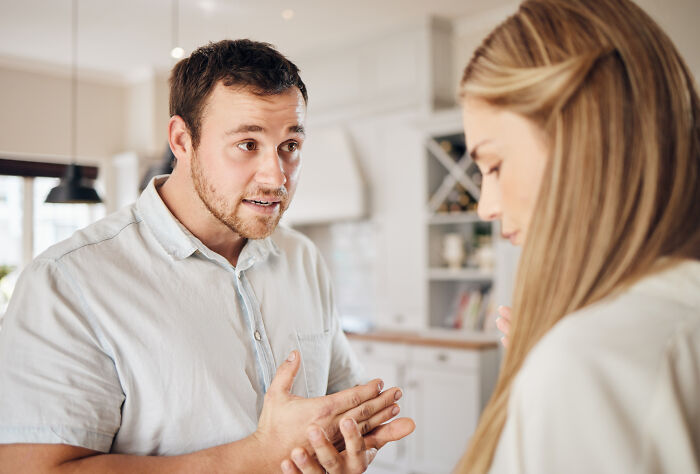 Man gesturing while mansplaining to a woman in a kitchen, illustrating men shooting themselves in the foot.