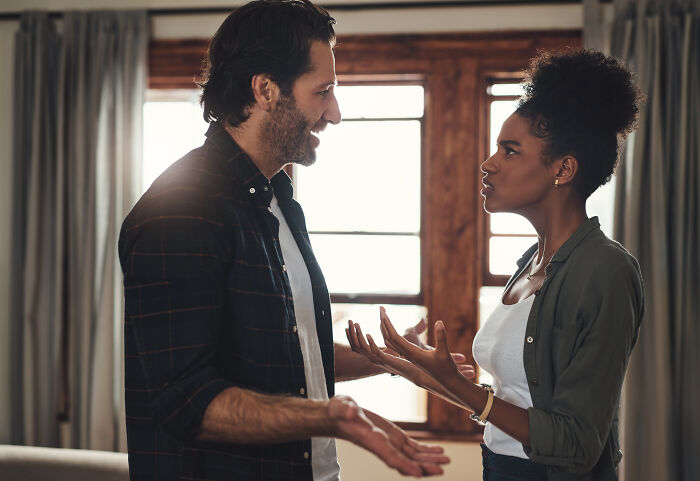 Man and woman having a heated argument indoors, illustrating the concept of mansplaining and communication conflict.