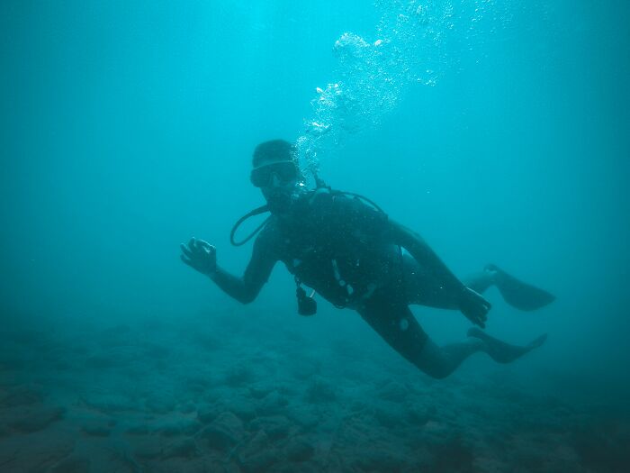 Scuba diver underwater surrounded by bubbles demonstrating calm and control in a deep sea environment.