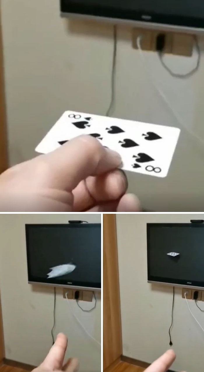 Hand holding a playing card throwing it at a TV screen, causing a disaster with the card stuck on the broken display.