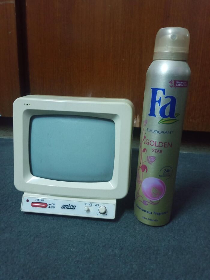 Small vintage TV with an old-fashioned design next to a modern deodorant can, creating a strange and confusing contrast.