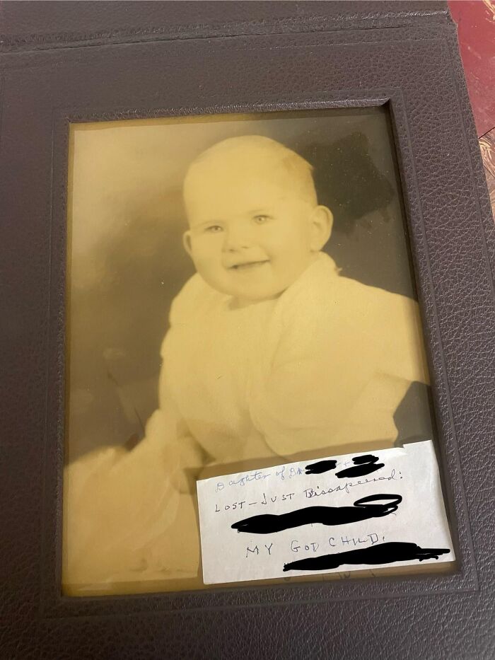 Sepia-toned photo of a baby in an old frame with a handwritten creepy note attached, found in an old home.