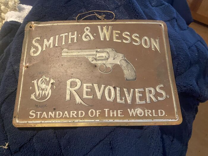 Vintage Smith & Wesson revolver metal sign found among creepy and bizarre items in an old home collection.