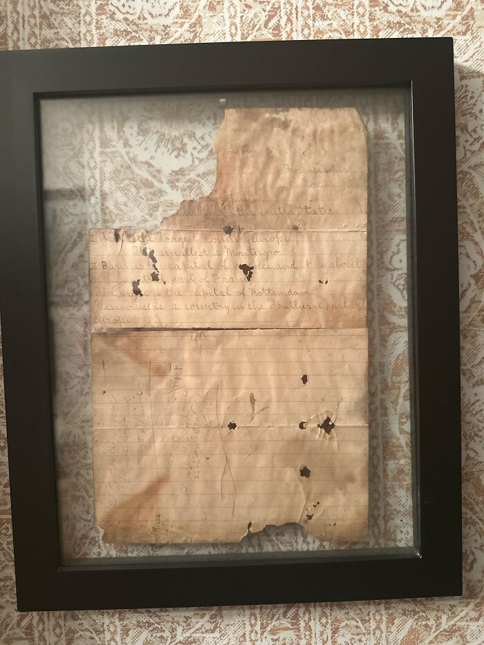 Faded, torn handwritten note framed on wall, a creepy and bizarre find in an old home.