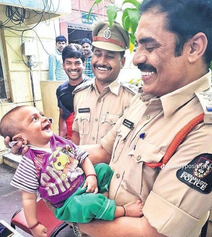 Smiling police officers holding a happy baby, showcasing uplifting moments of kindness and hope in the world.