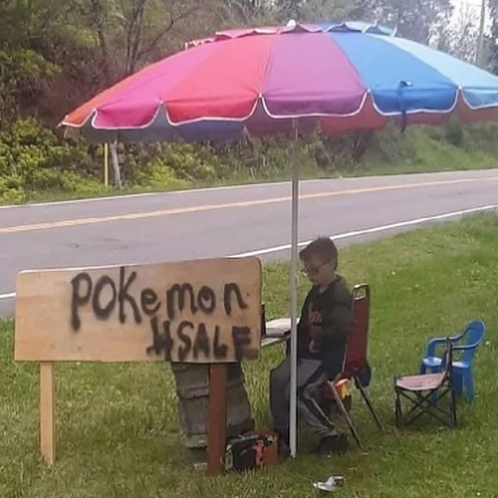 Child selling Pokémon cards under colorful umbrella by roadside, representing uplifting posts and positive moments in the world.