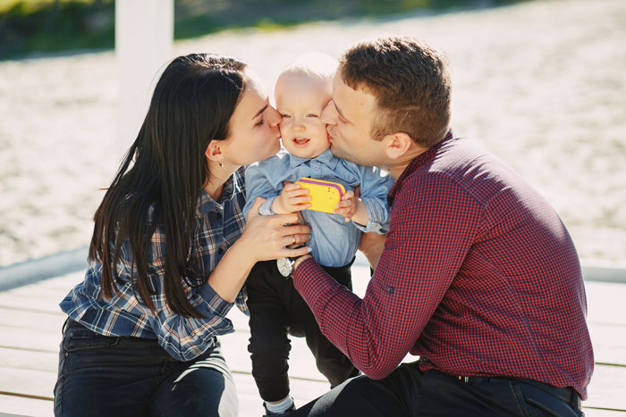 Young family with toddler sharing a tender moment outdoors, highlighting grandparents conflict over toddler and medical school decisions.