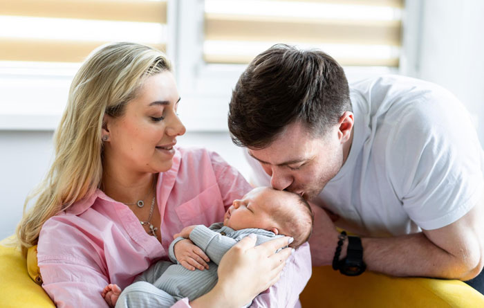 Mother holds baby while father kisses infant gently, illustrating a story about a surprise baby trap in a relationship.