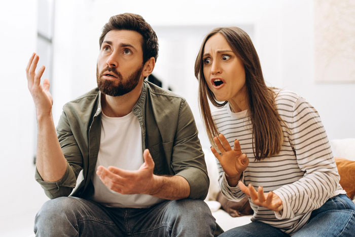 Couple in heated argument at home, woman humiliating teacher husband, expressing anger and frustration intensely.