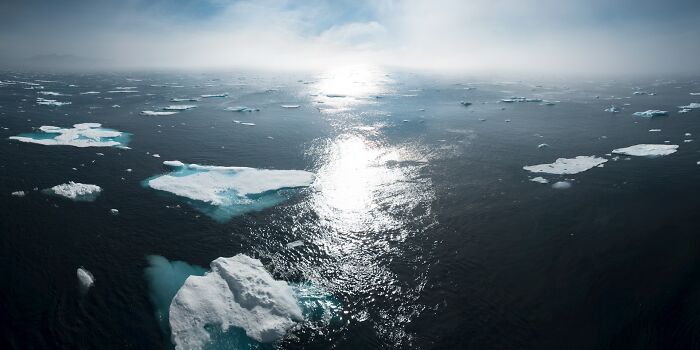 Melting icebergs floating in cold ocean water under a cloudy sky, symbolizing the impact of aging and change.