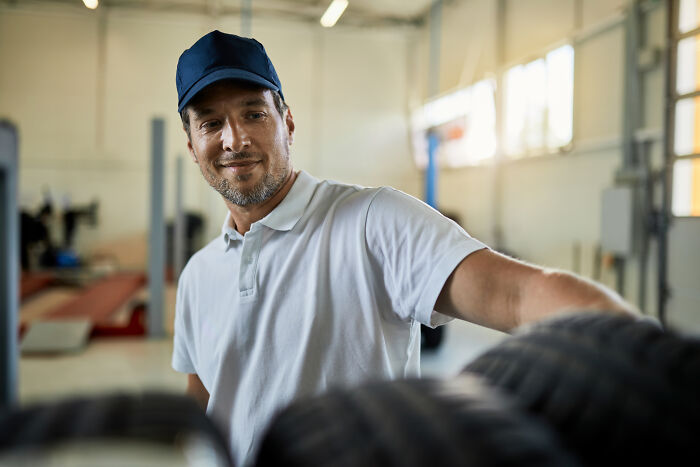 Man in a cap and white shirt inspecting tires in a workshop, related to scary encounters that still haunt people today.