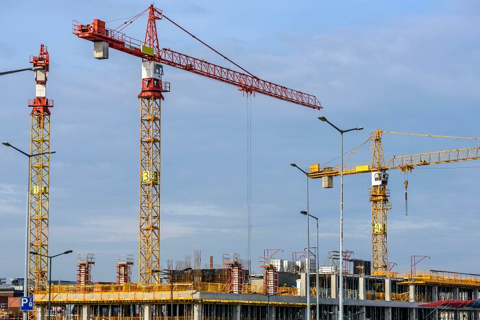 Construction site with cranes and scaffolding under a cloudy sky, depicting an eerie atmosphere for scary encounters.