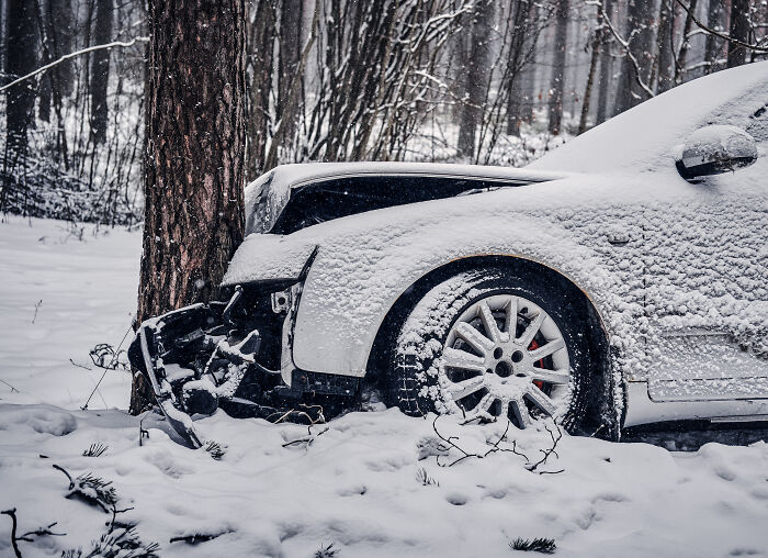 Car covered in snow crashed into tree in a snowy forest, illustrating a scary encounter that still haunts people today.