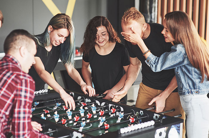 Group of friends playing foosball indoors, sharing laughs and enjoying casual fun in a friendly gathering.