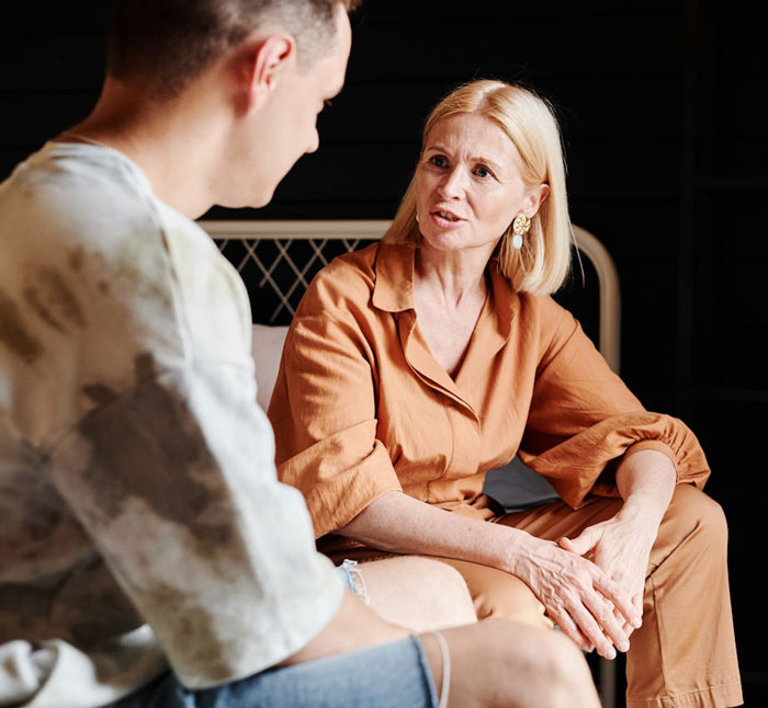 Woman in orange outfit talking seriously with man, reflecting a tense moment with boyfriend and pregnant mistress at work.