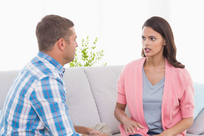 Man and woman in a living room having a tense conversation illustrating mansplaining and communication misunderstanding.