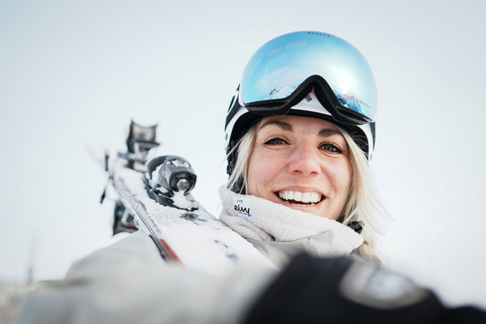 Smiling woman wearing ski gear outdoors, embodying the suspicious woman trusting her gut instinct concept.