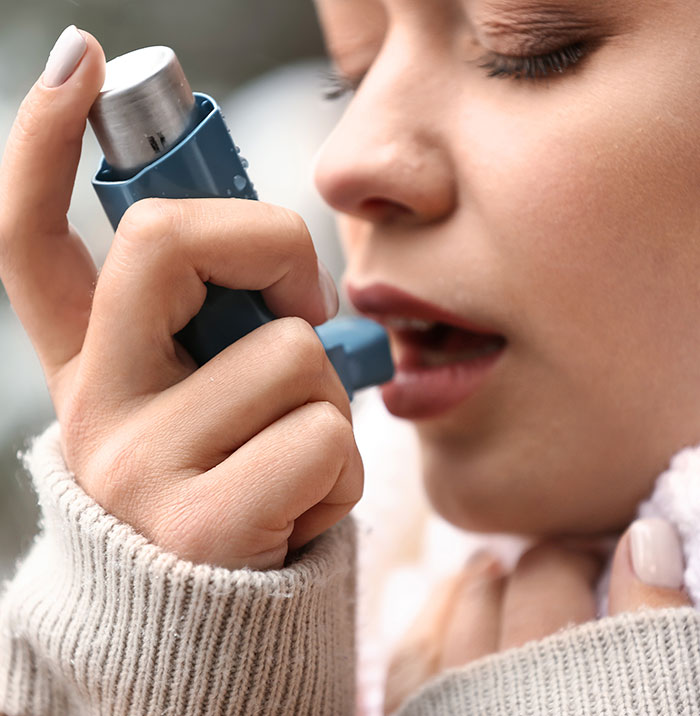 Close-up of a woman using an asthma inhaler, highlighting a harrowing diagnosis after faking depression for a nose job.