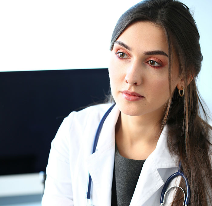 Female doctor in a white coat with stethoscope looking concerned, reflecting on hospital experiences so horrible.