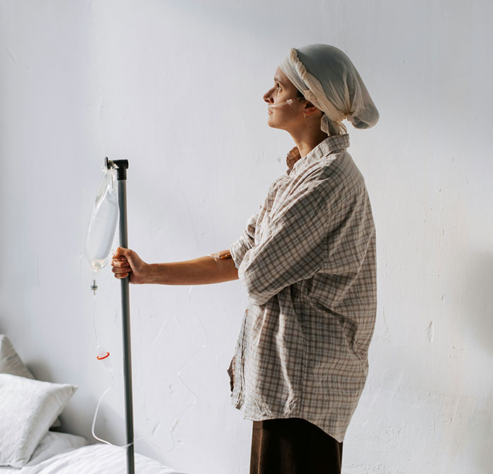 Patient with head wrap and IV drip stand, depicting hospital experiences and challenges in healthcare settings.