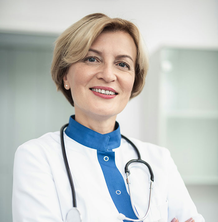 Smiling female doctor with short blonde hair and stethoscope in hospital environment representing hospital experiences.