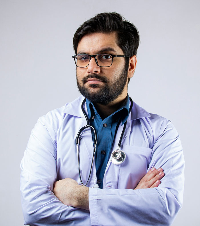 Male doctor with glasses and stethoscope looking serious, representing hospital experiences and healthcare challenges.