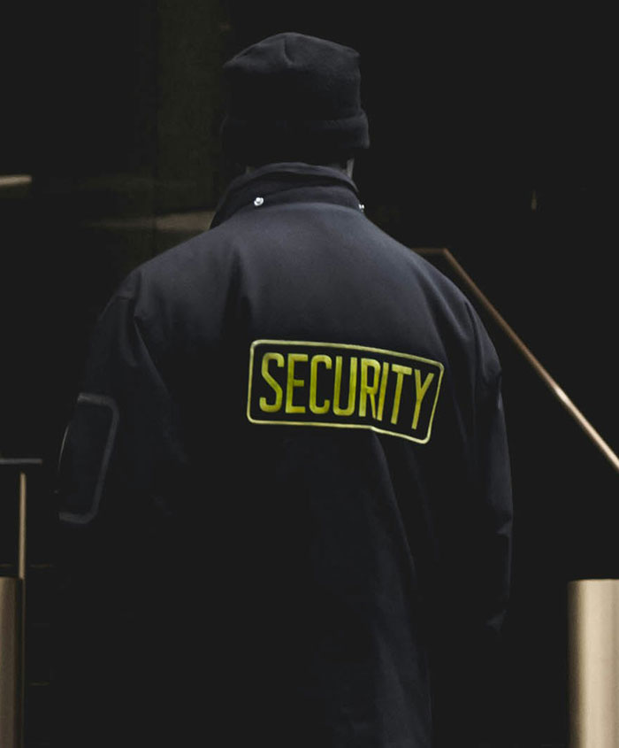 Security guard in dark uniform standing in a shadowy hospital corridor, highlighting hospital experiences challenges.