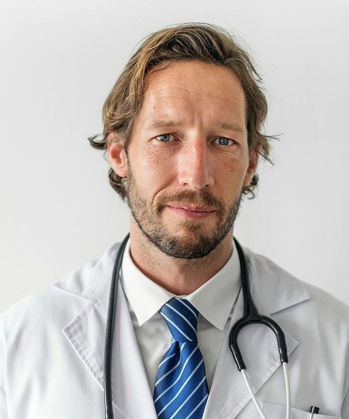 Male doctor with stethoscope wearing white coat and blue tie, representing hospital experiences and healthcare challenges.