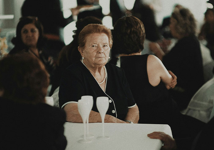 Elderly woman at a funeral gathering, looking solemn among other mourners during a memorable funeral moment.