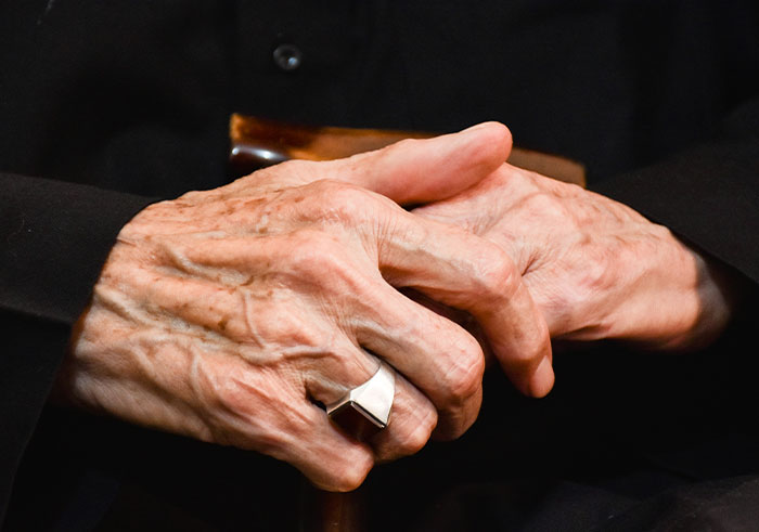 Close-up of elderly hands holding a walking cane, symbolizing memorable funeral moments with unexpected emotions.