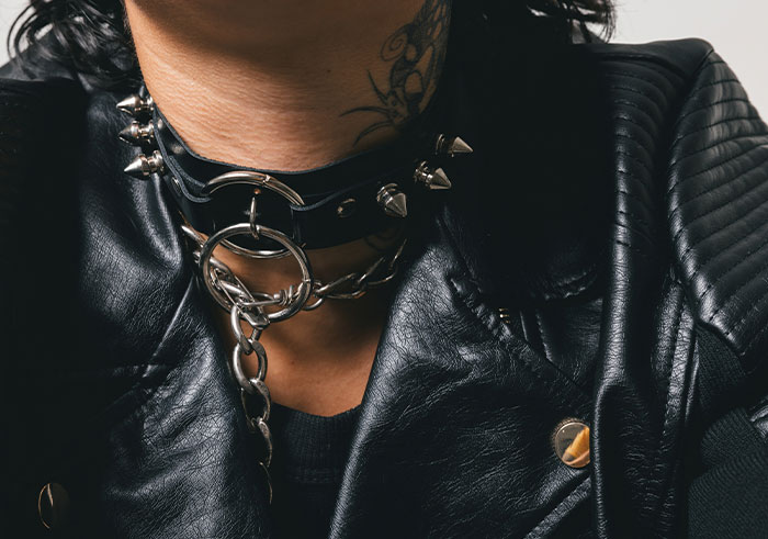 Close-up of person wearing a spiked choker and black leather jacket, reflecting alternative fashion and style.