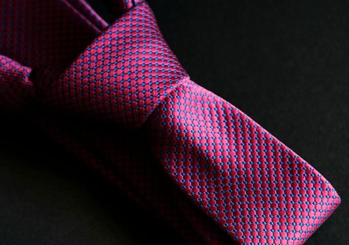 Close-up of a patterned tie on a dark background, symbolizing formal attire for memorable funeral moments.