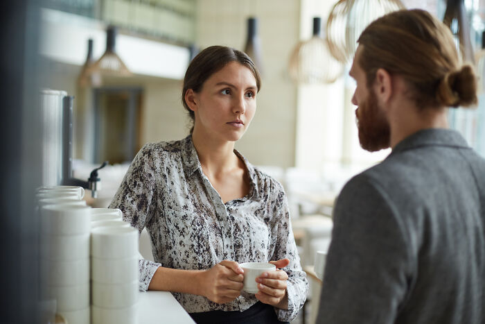 Woman listens intently to man speaking, capturing a moment reflecting mansplaining and communication issues between them.